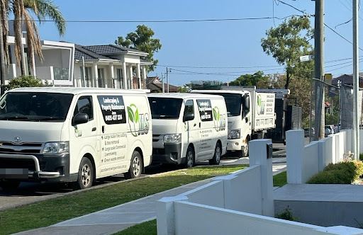 Two white vans and a truck parked along a suburban street, signwritten with a green leaf "JLMS" logo, "Landscaping & Property Maintenance" and Jason's mobile number